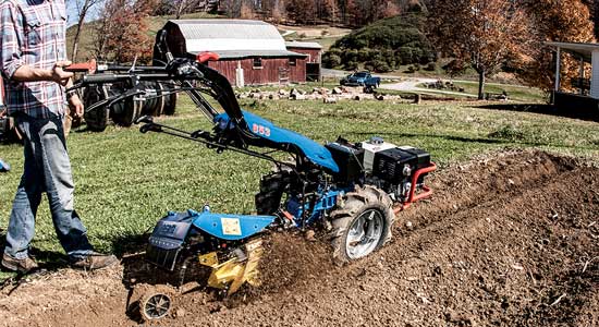 The rotary plow attachment equipped to the rear of a two-wheel walk-behind tractor can break new ground, power compost cover crops, build raised beds, create drainage ditches and more.